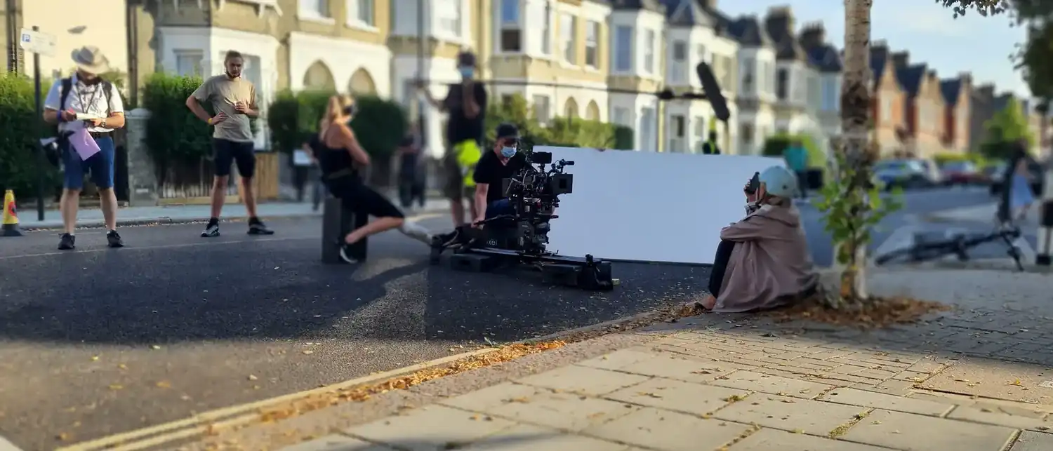 A street unit with blue screen, crew working around the camera.