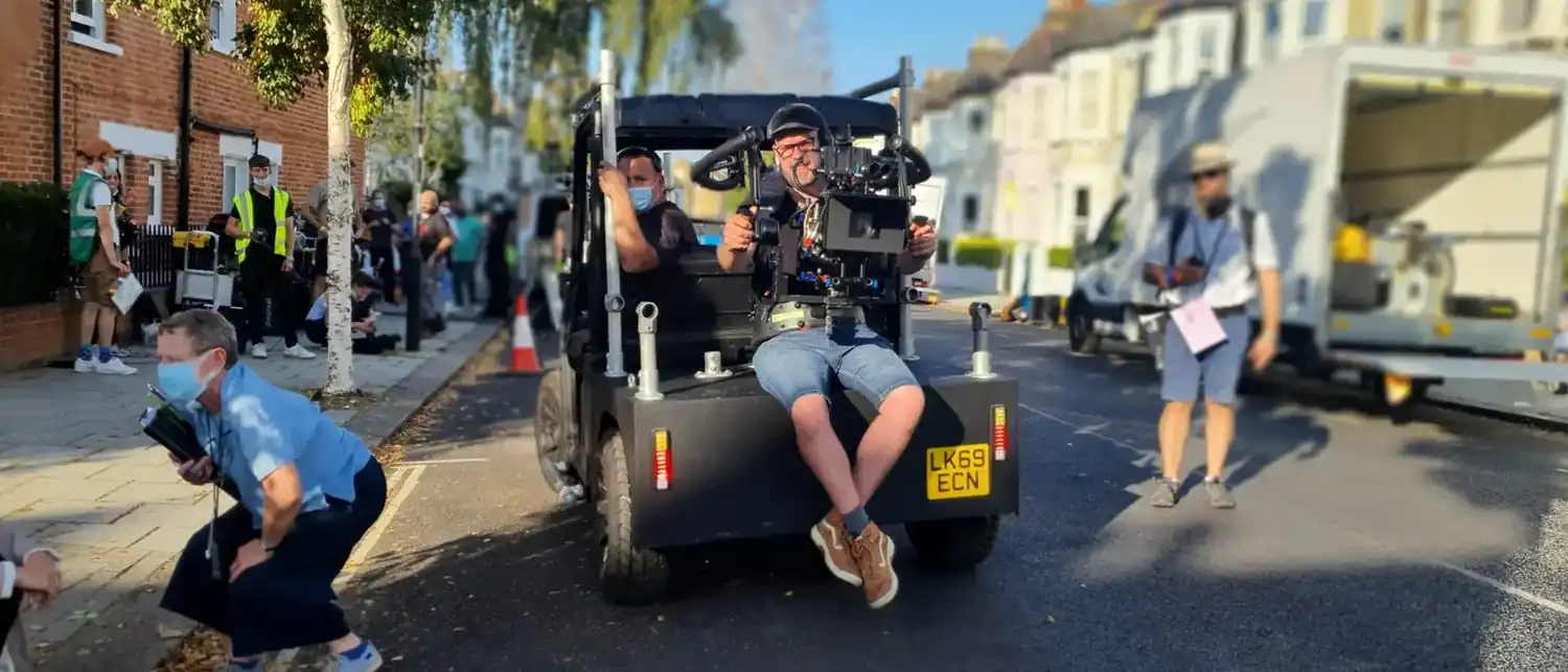 A dolly on track with crew, shooting on a street.