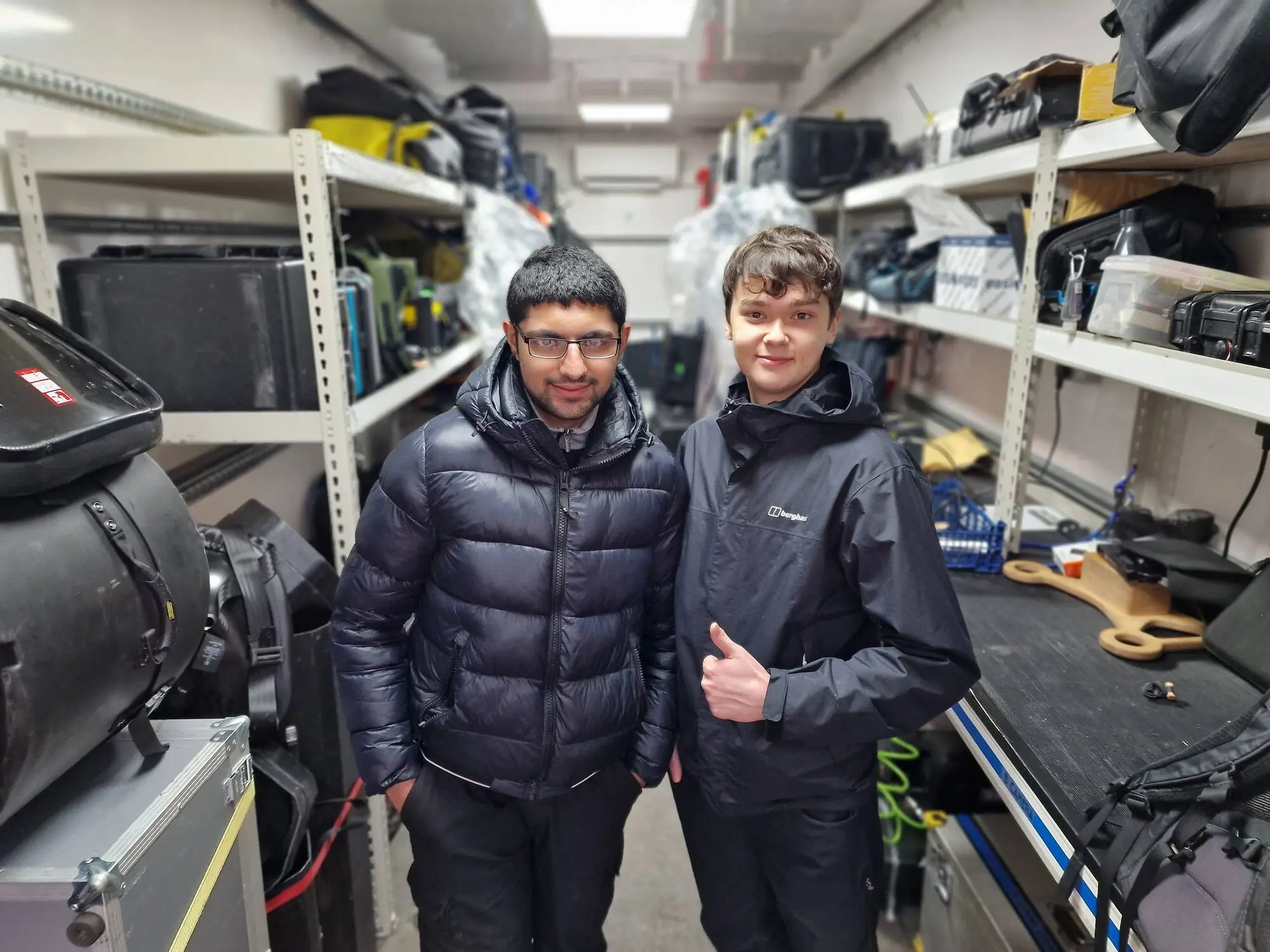 Two trainees in the camera truck, kit racked behind them