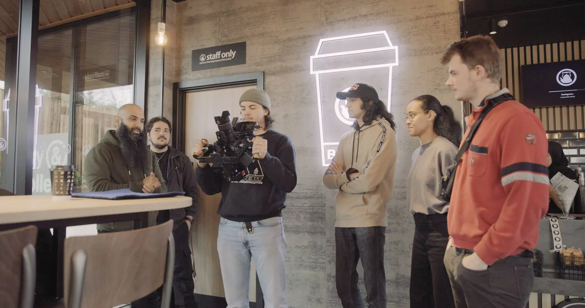 Filming inside a coffee shop set, crew watching