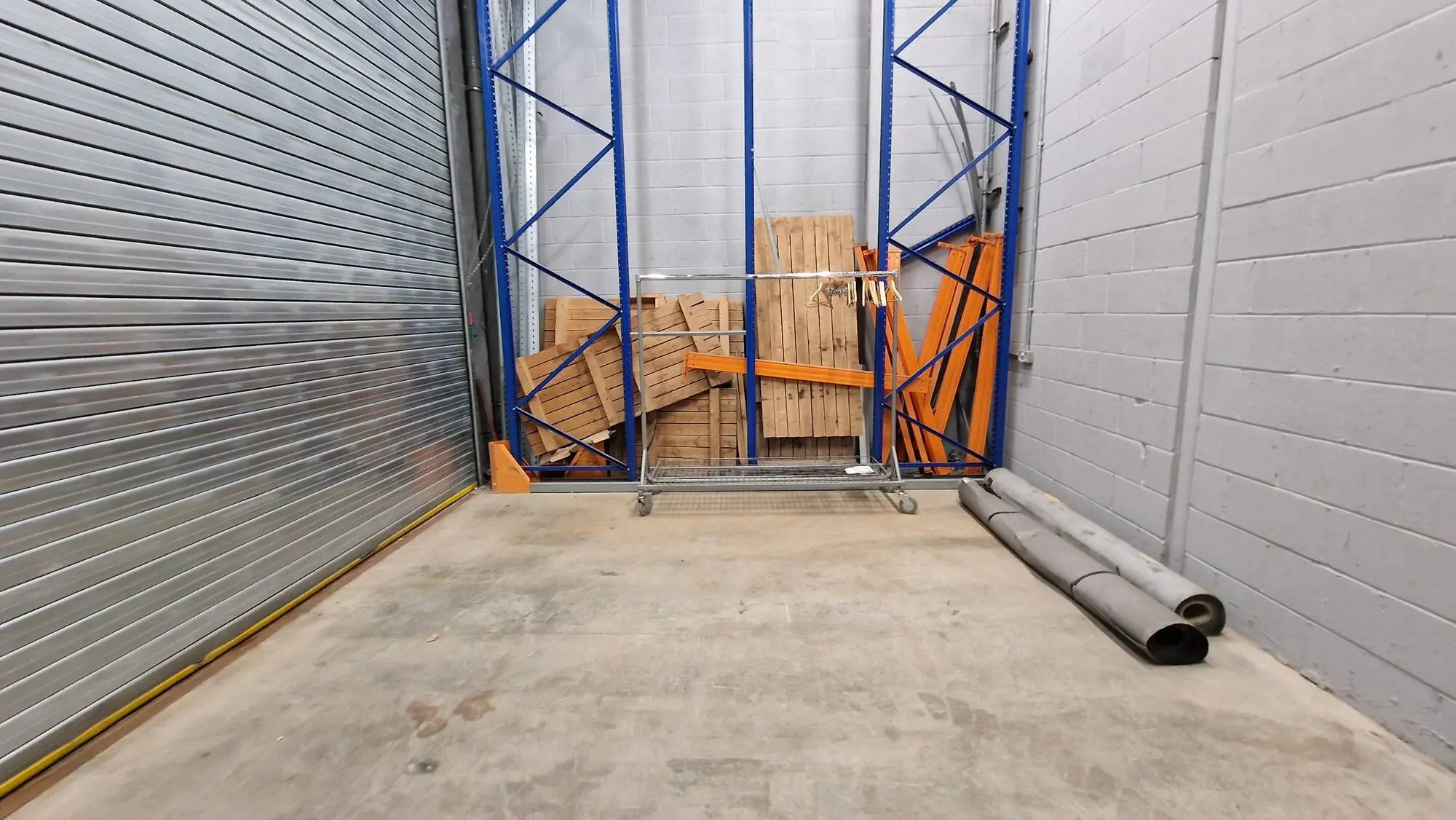 An empty workshop bay with racking, shutter open